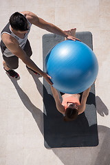 Image showing woman and personal trainer doing exercise with pilates ball