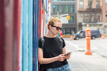 Image showing Woman using smartphones against colorful graffiti wall in New York city, USA.
