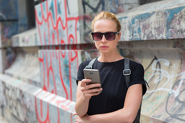 Image showing Woman using smartphones against colorful graffiti wall in New York city, USA.