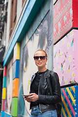 Image showing Woman using smartphone against colorful graffiti wall in New York city, USA.