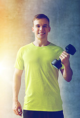 Image showing smiling man with dumbbell in gym