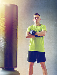 Image showing man with boxing gloves and punching bag in gym