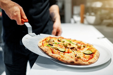 Image showing cook with baked pizza on peel at pizzeria