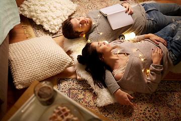 Image showing happy couple with garland lying on floor at home