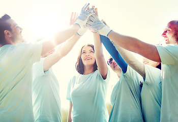 Image showing group of happy volunteers making high five in park