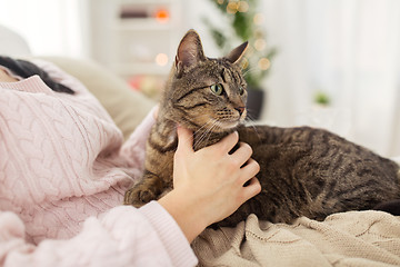 Image showing close up of owner with tabby cat in bed at home