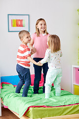 Image showing happy little kids jumping on bed at home