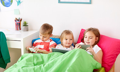 Image showing kids with tablet pc and smartphones in bed at home