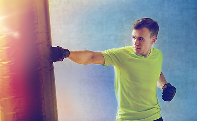 Image showing young man in gloves boxing with punching bag