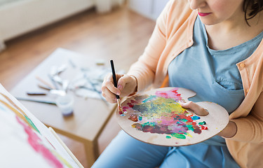 Image showing artist with palette and brush painting at studio