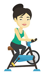 Image showing Young woman riding stationary bicycle.