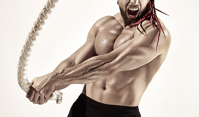 Image showing Attractive muscular man working out with heavy ropes.