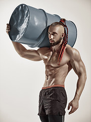 Image showing Fitness man with perfect body doing exercises with iron barrel