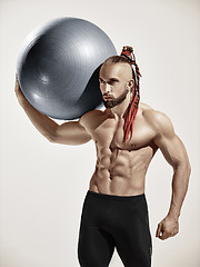 Image showing Muscular man holding fitness ball, standing isolated on white