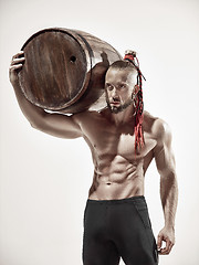 Image showing Fitness man with perfect body doing exercises with wooden barrel