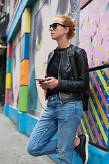 Image showing Woman using smartphone against colorful graffiti wall in New York city, USA.