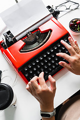 Image showing Woman hand working with bright red vintage typewriter