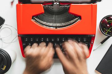 Image showing Man hand working with bright red vintage typewriter