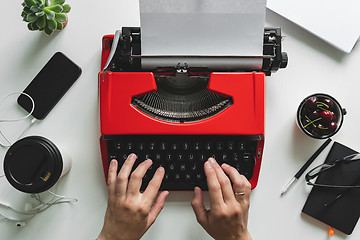 Image showing Woman hand working with bright red vintage typewriter