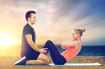 Image showing happy sportive couple doing sit-ups outdoor