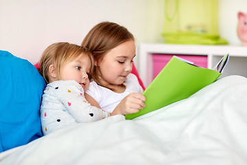 Image showing little girls or sisters reading book in bed