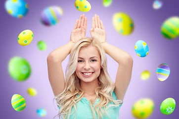 Image showing happy woman making bunny ears over easter eggs