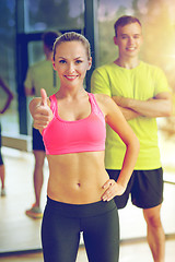 Image showing smiling man and woman showing thumbs up in gym