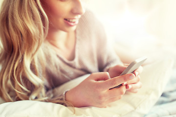 Image showing close up of woman with smartphone in bed at home