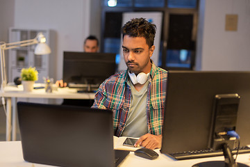 Image showing creative man with laptop working at night office