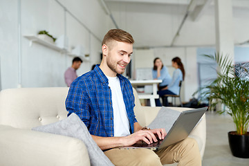 Image showing smiling man with laptop working at office