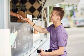 Image showing happy young man paying money at food truck