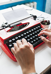 Image showing Woman hand working with bright red vintage typewriter