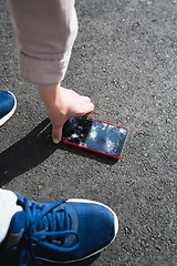 Image showing Woman raises from the ground a broken smartphone