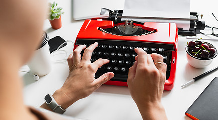 Image showing Woman hand working with bright red vintage typewriter