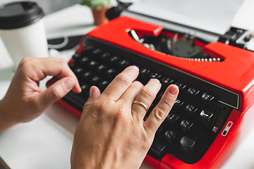 Image showing Woman hand working with bright red vintage typewriter