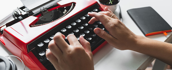Image showing Woman hand working with bright red vintage typewriter