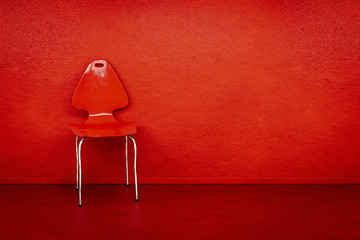 Image showing red chair at a red wall with space for your content