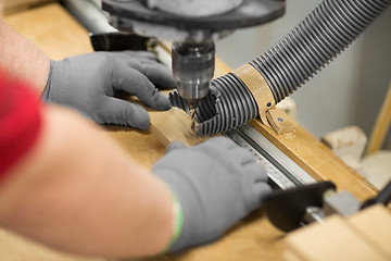 Image showing carpenter with drill press and board at workshop