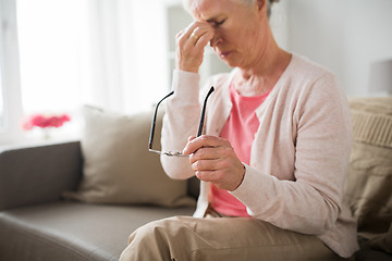Image showing senior woman with glasses having headache at home