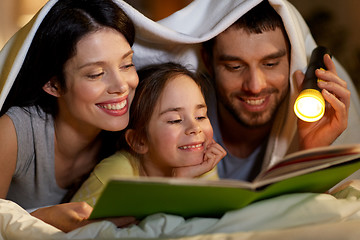 Image showing happy family reading book in bed at night at home