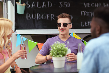 Image showing friends with drinks sitting at table at food truck