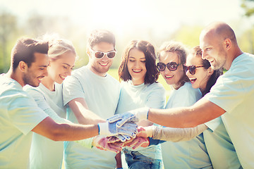 Image showing group of volunteers putting hands on top in park