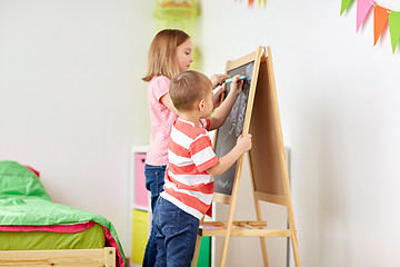 Image showing happy kids drawing on chalk board at home