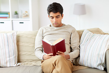 Image showing man sitting on sofa and reading book at home