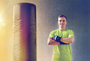 Image showing man with boxing gloves and punching bag in gym