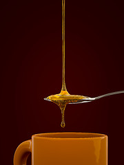 Image showing a spoon full of golden honey over a tea mug