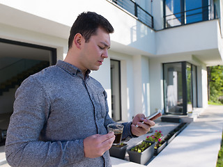 Image showing man using mobile phone in front of his luxury home villa