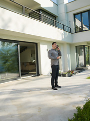 Image showing man using mobile phone in front of his luxury home villa