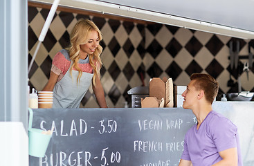 Image showing saleswoman at food truck serving male customer