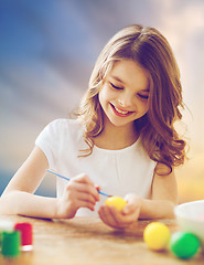 Image showing happy girl coloring easter eggs